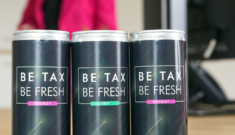 Drei Dosen mit der Aufschrift "Be tax, be fresh" stehen auf einem Tisch. 