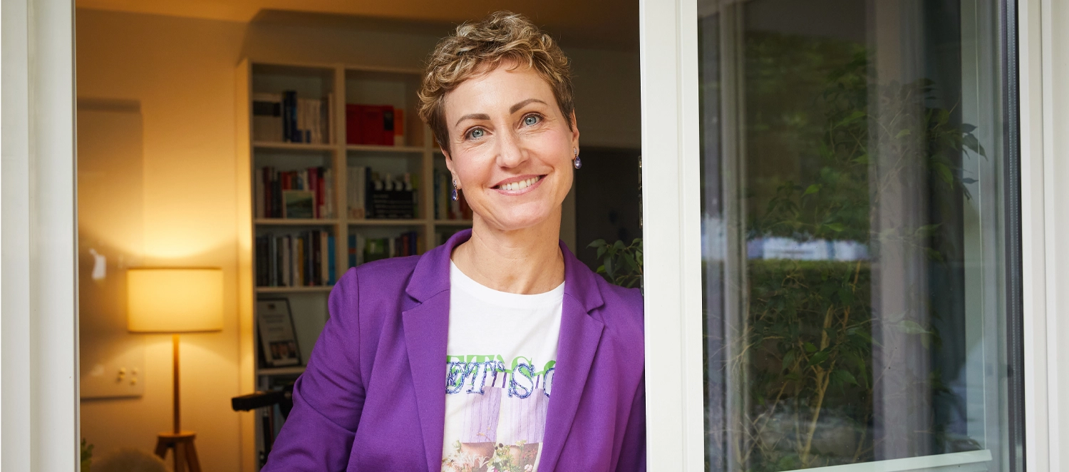 Eine Frau steht an einer geöffneten Tür.