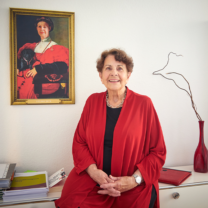 Eine Frau sitzt auf einem Tisch und schaut in die Kamera.