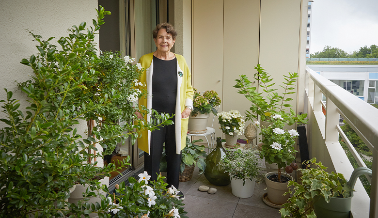 Eine Frau steht auf einem Balkon mit Topfpflanzen.