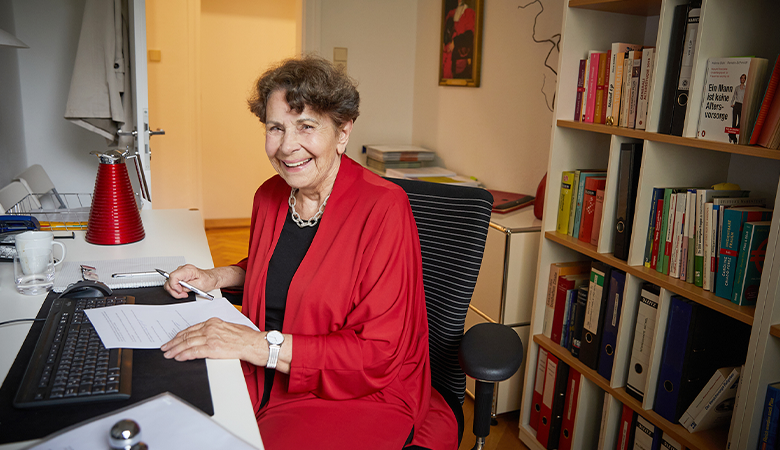 Eine Frau sitzt an ihrem Schreibtisch mit einer Computertastatur  vor sich. 
