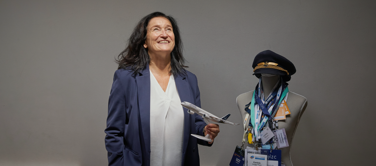 Eine Frau steht mit einem Spielzeugflugzeug in der Hand in einem Raum und schaut nach oben.