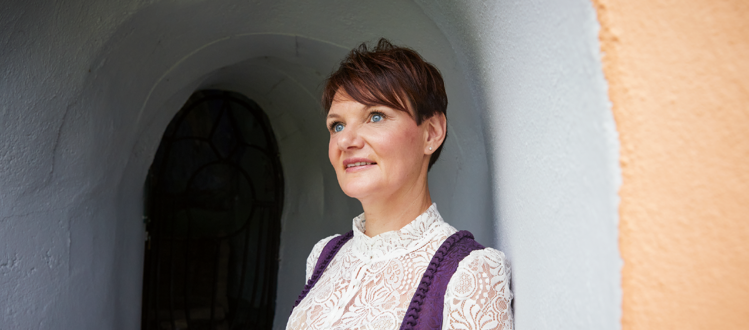 Eine Frau steht in einem Torbogen und schaut in die Ferne.
