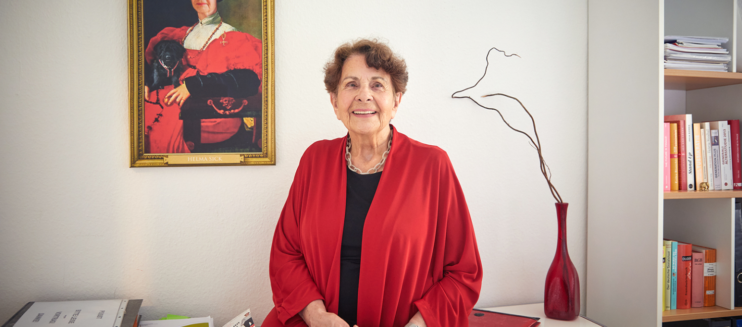 Eine Frau sitzt auf einem Tisch und schaut in die Kamera. 