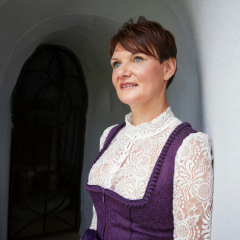 Eine Frau steht in einem Torbogen und schaut in die Ferne. 