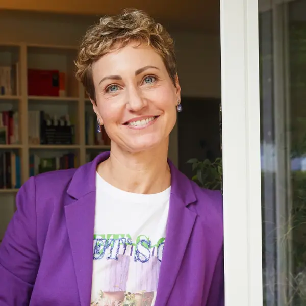 Eine Frau steht an einer geöffneten Tür. 