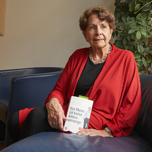 Eine Frau sitzt auf einem Sofa und hält ein Buch mit dem Titel 
