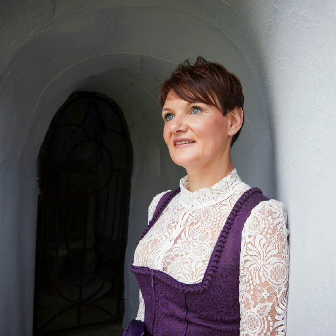 Eine Frau steht in einem Torbogen und schaut in die Ferne.