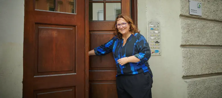 Eine Frau öffnet eine Haustür und ist kurz davor, einzutreten.