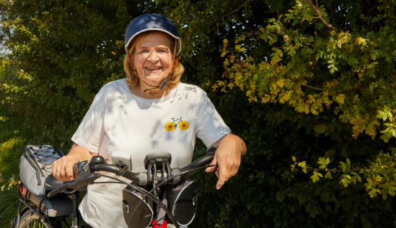 Eine Frau mit Fahrradhelm stützt sich auf den Lenker ihres Fahrrads ab. 