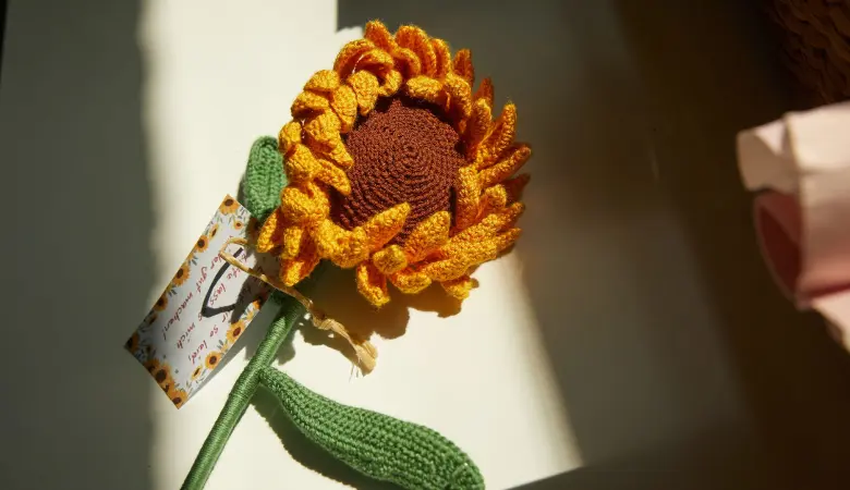 Eine gehäkelte Sonnenblume hängt an einer Wand. 