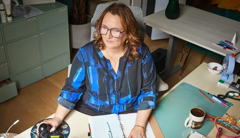 Eine Frau sitzt an einem Schreibtisch und schaut auf den Computerbildschirm. 