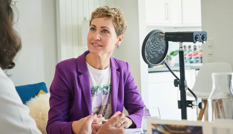 Zwei Frauen sitzen an einem Tisch mit einem Mikrofon. 