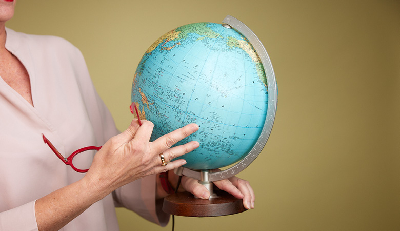 Nahaufnahme: Irene Wagner hält einen Globus in einer Hand; mit der anderen dreht sie die Weltkugel.