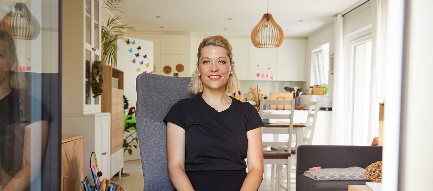 Helen Orgis sitzt im Schneidersitz auf einem Stuhl in ihrer Wohnung.