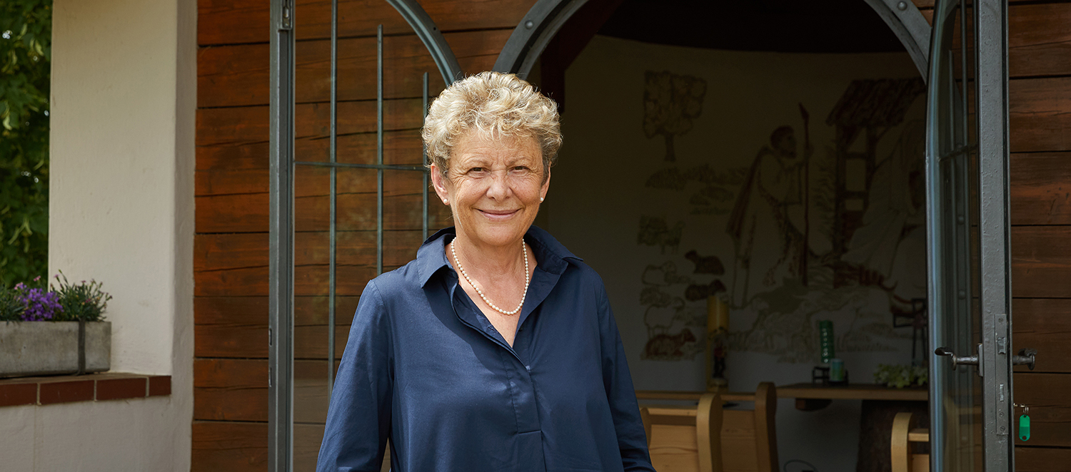 Brigitte Ganslmeier steht vor einer Kapelle.