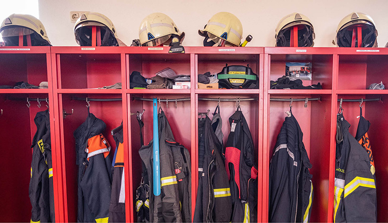 Eine Reihe von offenen Spinden mit Feuerwehrkleidung.