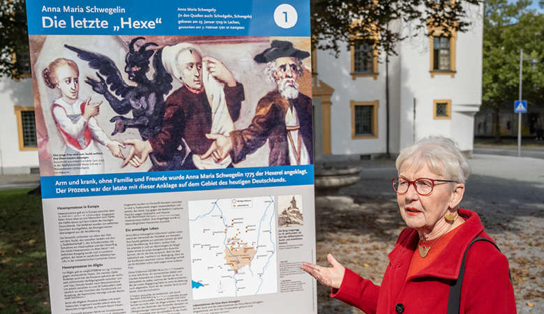 Elisabeth Brock steht vor einer Informationstafel mit dem Titel: Die letzte „Hexe“.