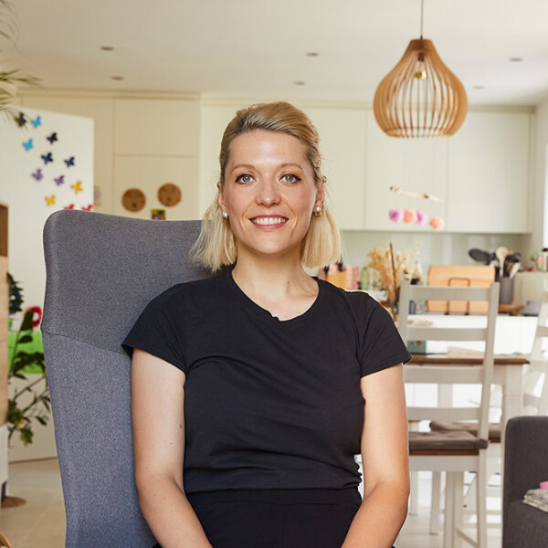 Helen Orgis sitzt im Schneidersitz auf einem Stuhl in ihrer Wohnung.