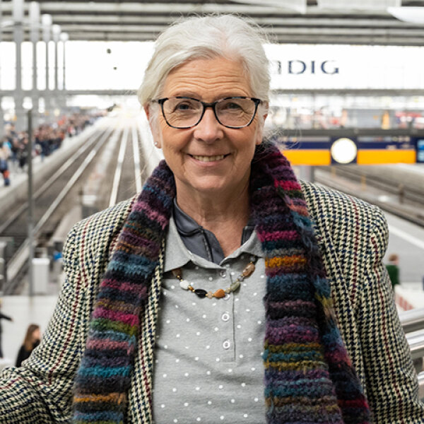 Marianne Schweinesbein steht auf einer Empore in der Gleishalle des Münchner Hauptbahnhofs.