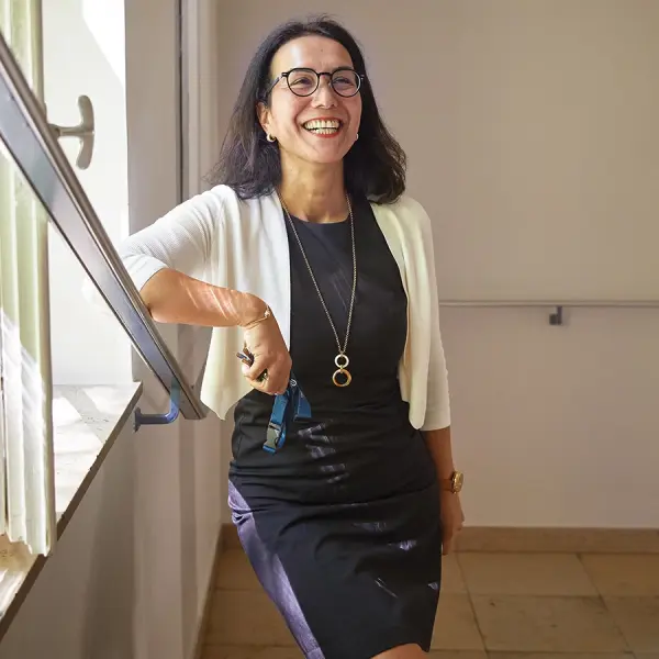 Eine Frau lehnt auf einem Treppenhandlauf und lächelt. 