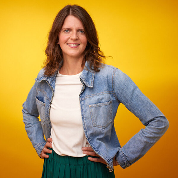 Porträtfoto: Daniela Nuber-Fischer. Sie hat schulterlange braune Haare und trägt T-Shirt, Jeansjacke und einen grünen Rock. 