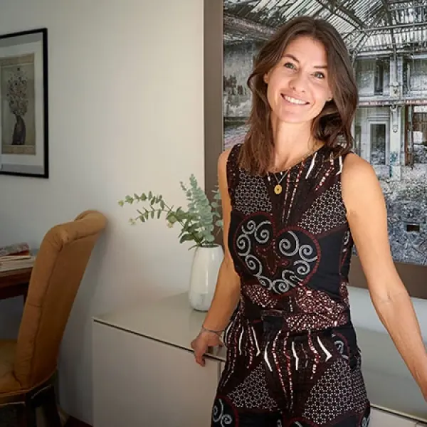 Eine Frau steht angelehnt an ein Sideboard in einem Wohnzimmer. 