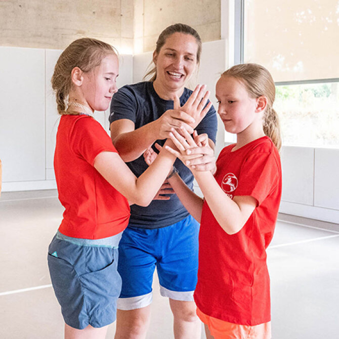 In einer Sporthalle: Trainerin Julia Harms und mehrere Mädchen bei einer Übung.