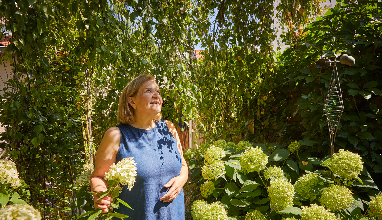 Eine Frau im Sommerkleid steht in einem Garten mit Hortensien.