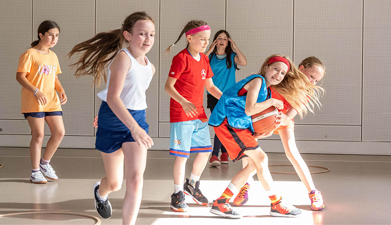 In der Sporthalle: Die U10 spielt Basketball; zwei Mädchen kämpfen um den Ball.