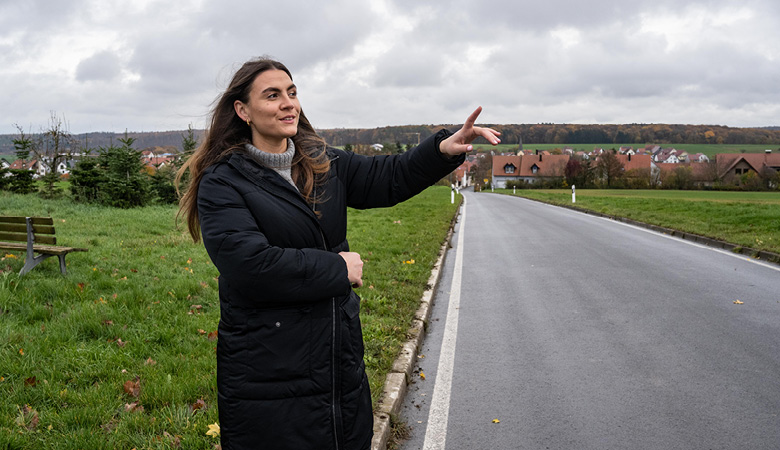 Lisa-Marie Schmitt steht am Straßenrand und deutet auf die Landschaft.