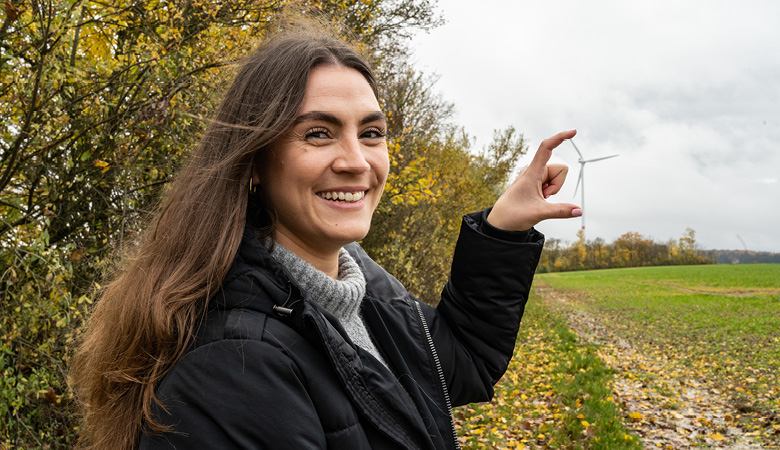 Lisa-Marie Schmitt zeigt mit ihren Fingern auf ein Windrad. 