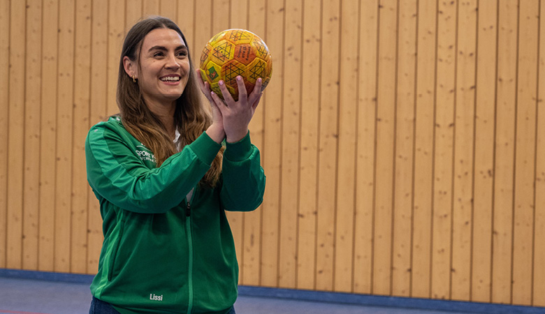 In einer großen Sporthalle. Lisa-Marie Schmitt hält einen Korbball und setzt zum Wurf an.