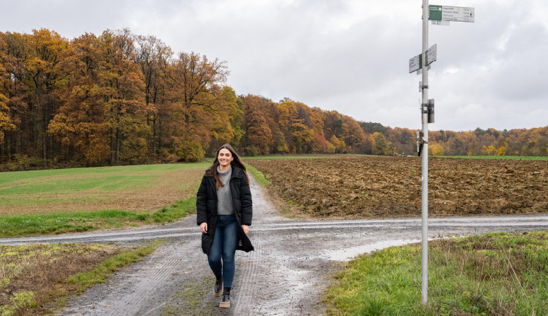 Eine Wegkreuzung vorm Wald: Lisa-Marie Schmitt geht auf die Kamera zu.