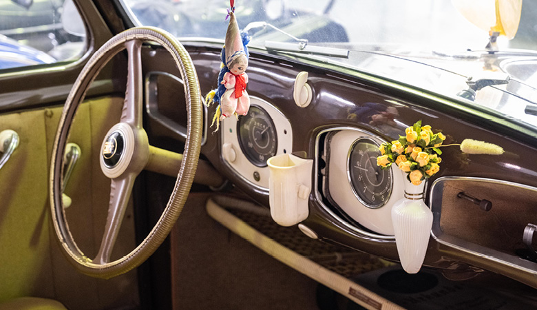 Blick aufs Armaturenbrett eines alten VW Käfer, das unter unter anderem mit einer Vase ausgestattet ist.