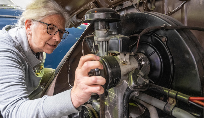Marianne Schweinesbein wirft einen fachkundigen Blick in  den Motorraum eines Oldtimers.