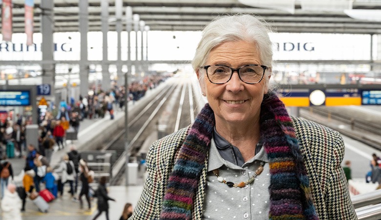 Marianne Schweinesbein steht auf einer Empore in der Gleishalle des Münchner Hauptbahnhofs.