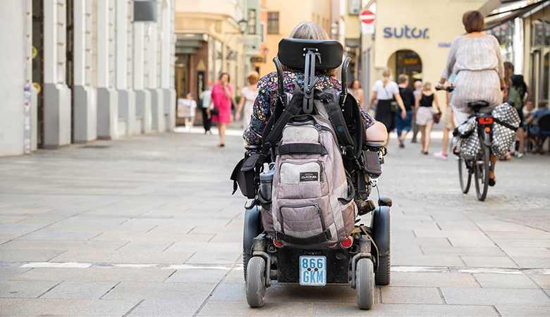 Aufnahme von hinten: Wiebke Richter fährt im E-Rollstuhl durch die Innenstadt.