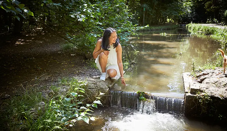 Frau an einem Bach in einem Wald. 