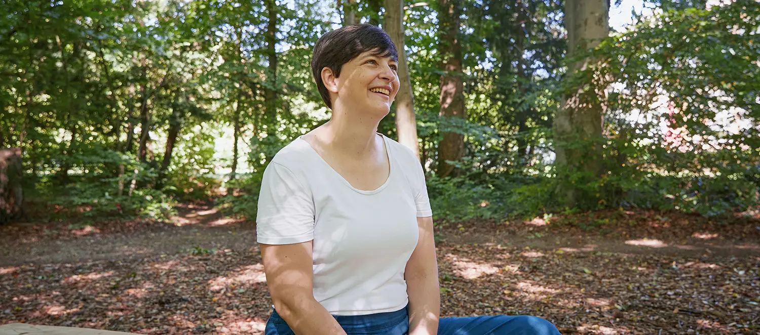 Frau im Wald sitzend.