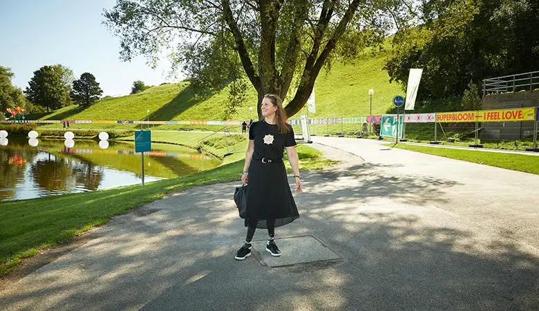 Frau in einem Park, vor einem Teich stehend. 